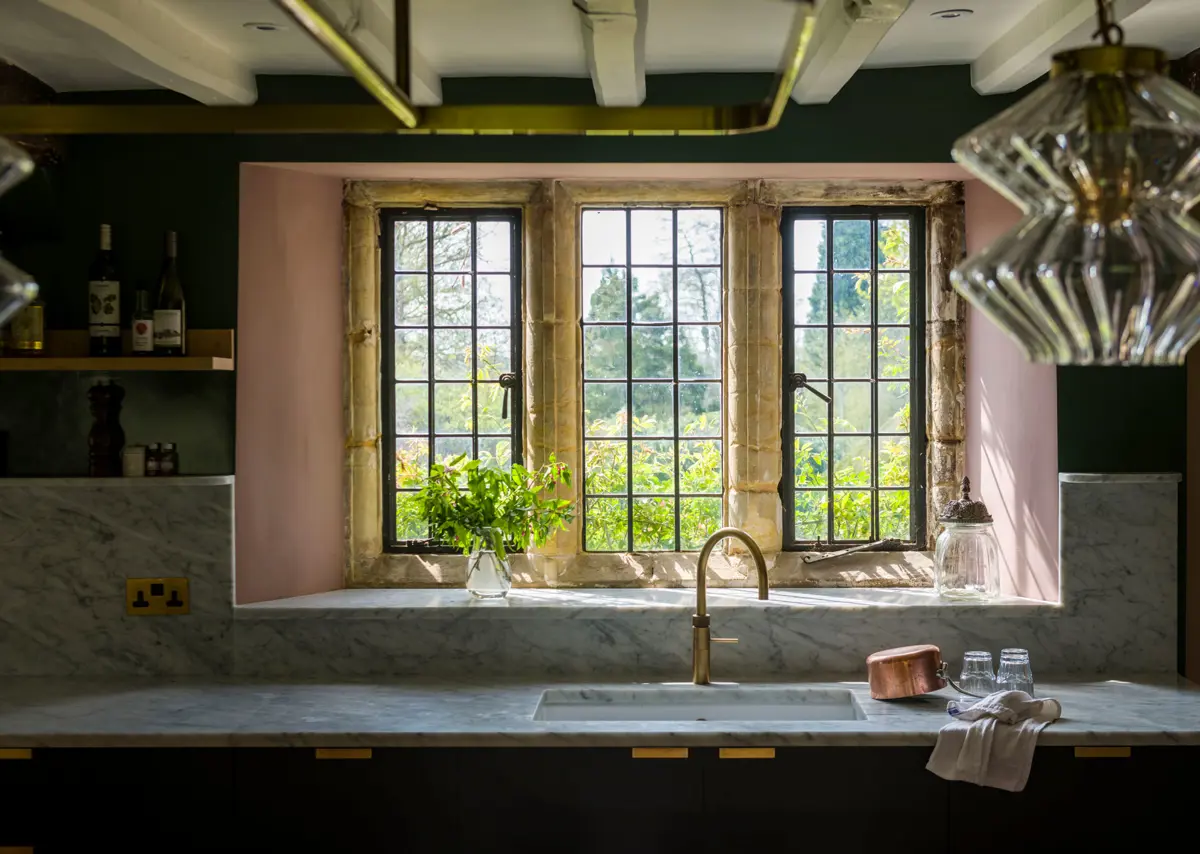 Quiet luxury of a Quooker hot water tap set against Carrara Marble and elegant Richlite cabinetry with antique brass.  English kitchen design at its best.
