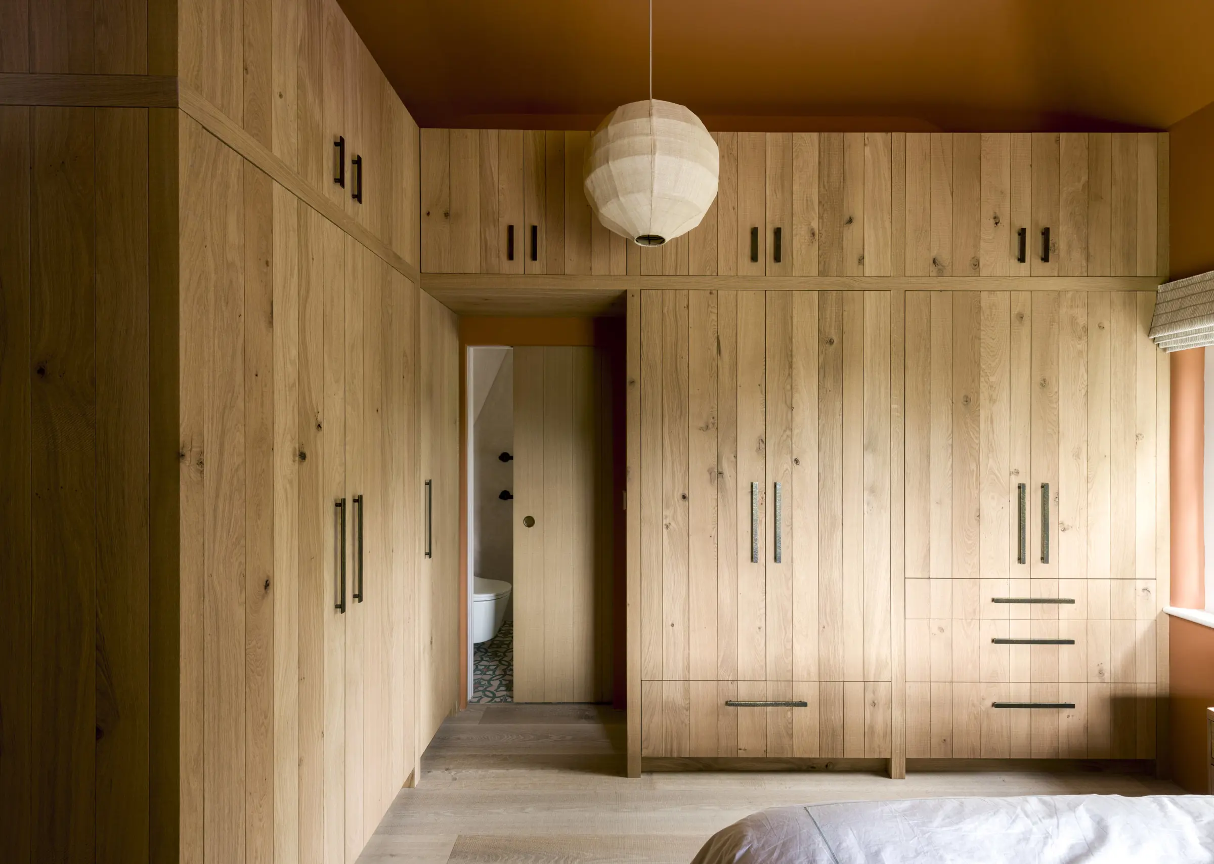 Bespoke wardrobe storage wraps around this terracotta bedroom