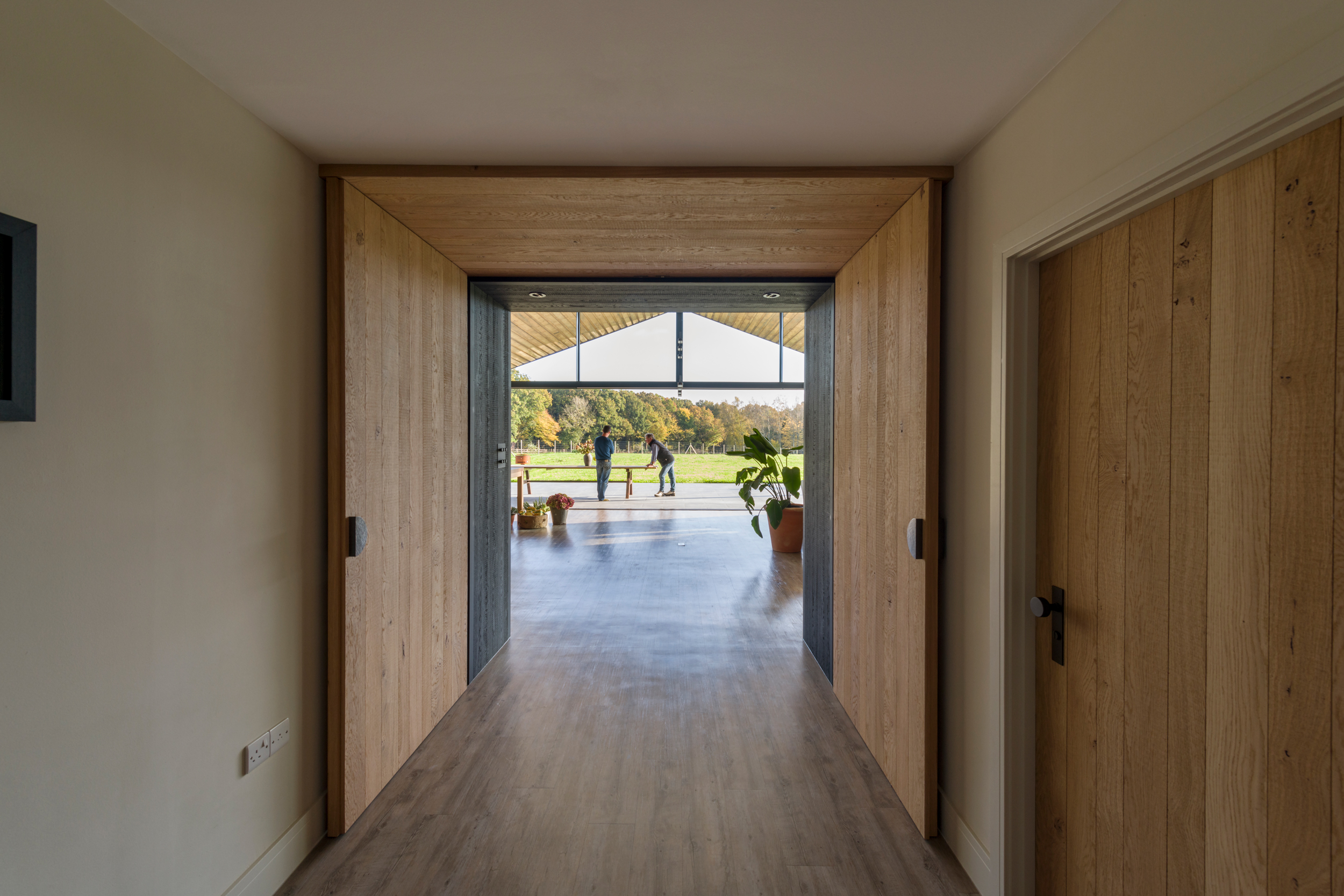 A grand internal entrance of handmade bespoke solid oak double doors with Ged Kennett hardware welcomes you into the large kitchen living space in this contemporary rural Sussex barn.