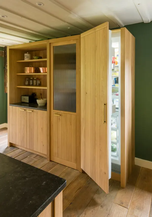 Band-sawn oak clad walls cleverly conceal a walk in pantry housed within an old inglenook and the family sized fridge-freezer.