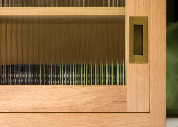 Bespoke kitchen sliding door cabinetry in oak with fluted glass and brass hardware, made the traditional way using local British craft.