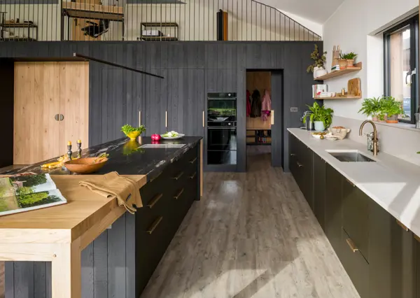 Integrated kitchen cooking appliances stacked at a comfortable use friendly height, framed in blackened band-sawn oak. A sliding pocket door with Ged Kennett solid brass bespoke handle reveals the utility and boot room behind.