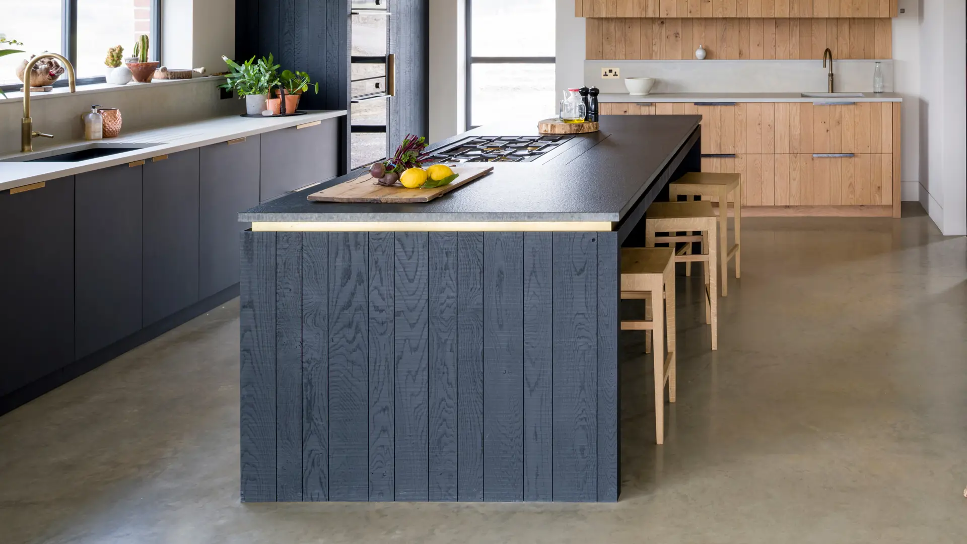 Bespoke contemporary kitchen featuring handcrafted blackened band-sawn oak and raw band-sawn oak set against a smooth Richlite sink cabinetry in front of a window with views over the Sussex Weald.