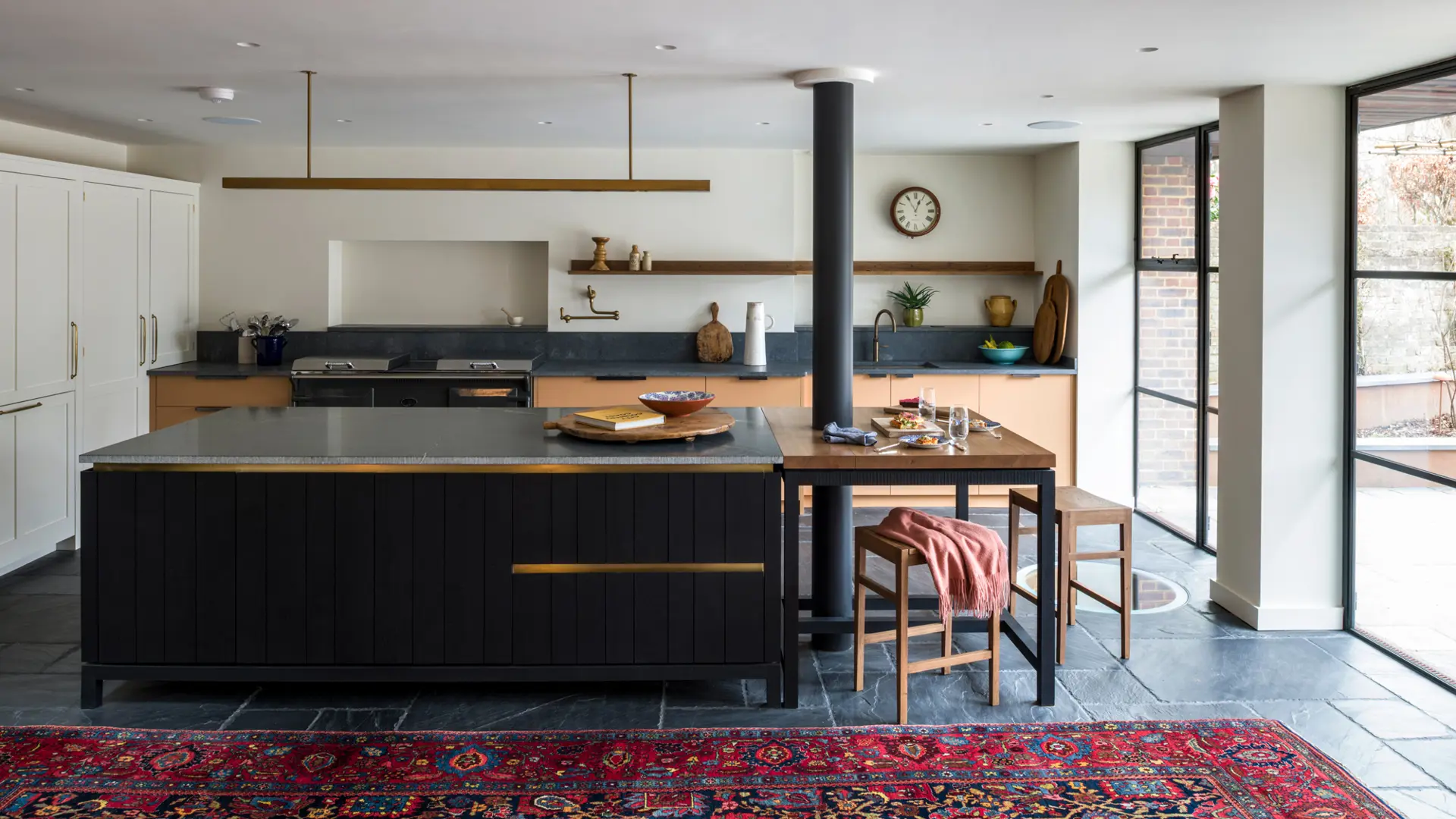 A bespoke contemporary kitchen featuring a handcrafted kitchen island in blackened band-sawn oak, slate flagstones, and a tooled edge granite countertop, blending artisan craftsmanship with timeless design.