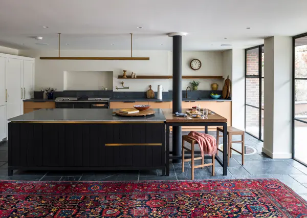 A bespoke contemporary kitchen featuring a handcrafted kitchen island in blackened band-sawn oak, slate flagstones, and a tooled edge granite countertop, blending artisan craftsmanship with timeless design.