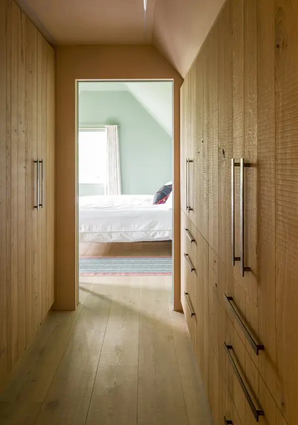 A walk-in wardrobe concealed behind beautiful oak-clad doors