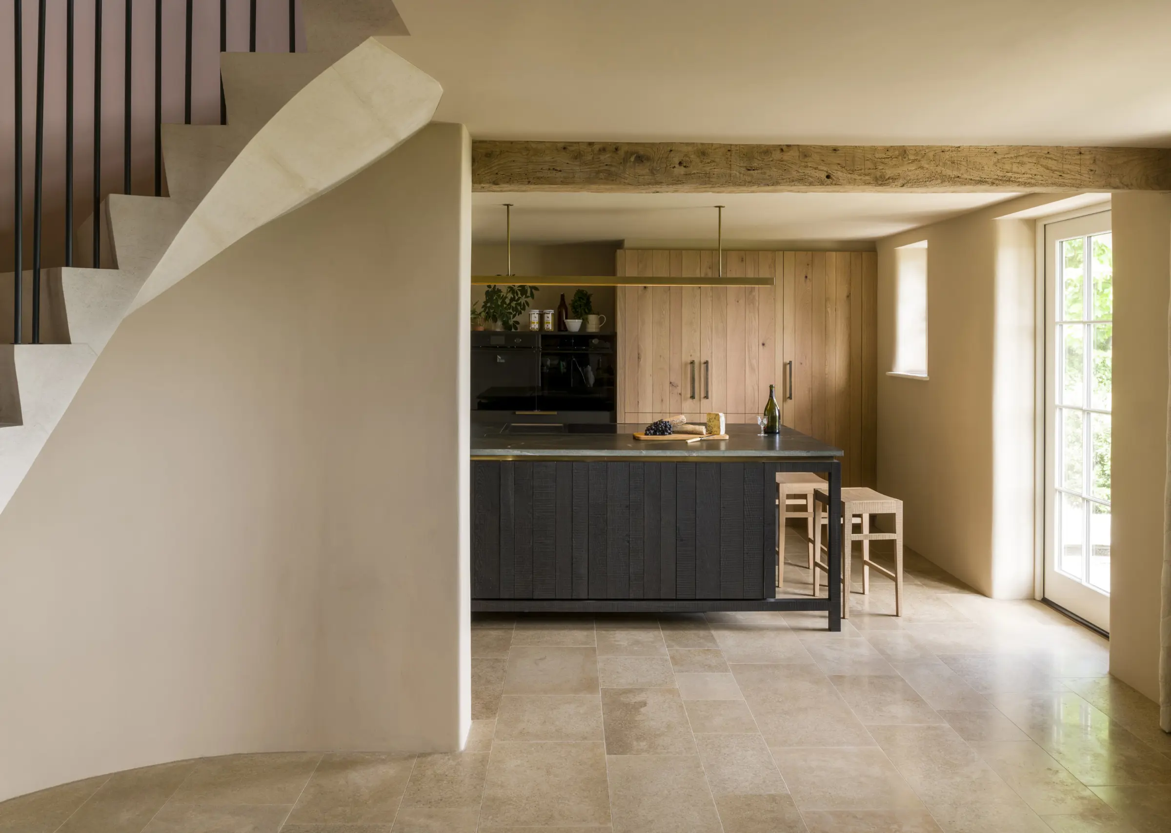 A kitchen framed by old beams and a new helix-stone spiral staircase