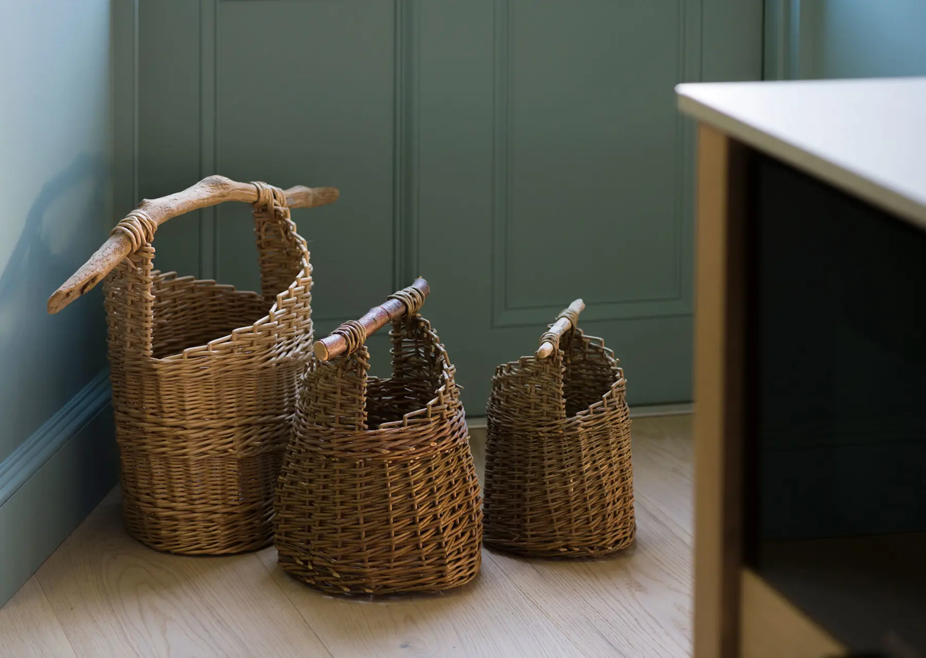 Three handwoven baskets with raw wooden handles on the kitchen floor provide a rustic farmhouse kitchen feel in this Scottish kitchen project.